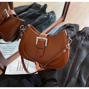 Detailed close-up of brown faux leather underarm bag with silver square metal buckle