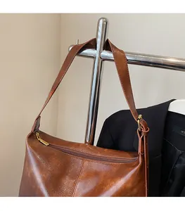 Détail de la texture cuir marron vintage et bandoulière réglable sur un sac à bandoulière