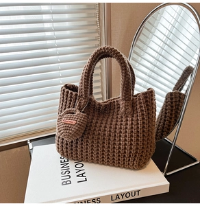 Detail of dark brown knit tote bag featuring a handmade heart charm and mesh texture
