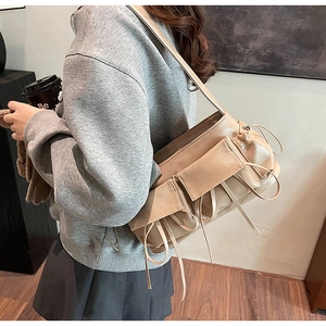 Detailed close-up of beige shoulder bag with bow drawstrings and external pockets