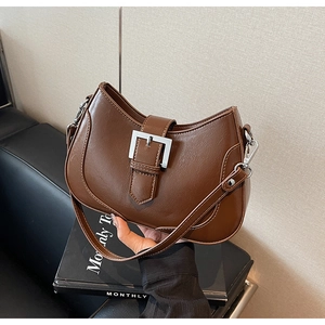 Detail of dark brown leather crescent bag with silver buckle and adjustable shoulder strap