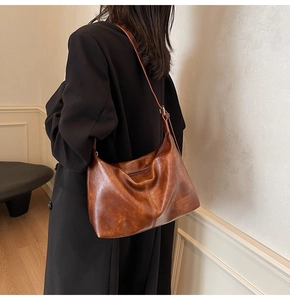 Vue latérale détaillée d'un sac cabas marron vintage avec logo sur un manteau noir élégant