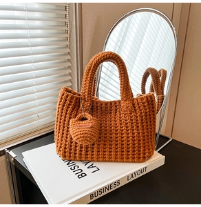 Detail of orange knit bucket bag with handmade leather label on a decorative book