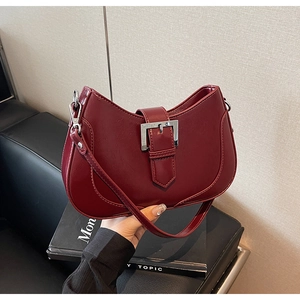 Close-up of burgundy glossy faux leather underarm bag featuring a large silver buckle
