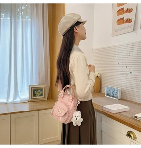 Pink mini crossbody bag shown on a model with cute plush dog pendant detail