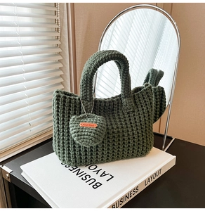 Detailed knit texture of dark green handmade bucket bag with apple charm and label