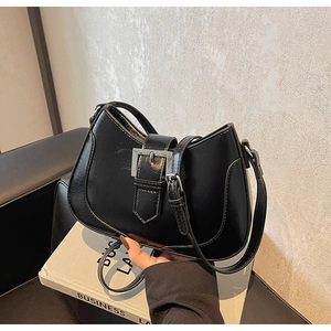 Detailed view of black underarm bag featuring a metallic silver buckle and leather texture