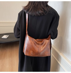 Détail d'un sac cabas vintage en cuir marron ciré avec écusson et fermeture éclair