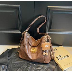 Detail of vintage brown hobo bag with gold metal emblem and soft matte leather texture