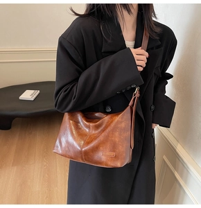 Sac hobo vintage en similicuir marron porté par un mannequin sur un blazer noir oversize