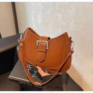 Detail view of caramel faux leather crescent bag with silver buckle and thin strap