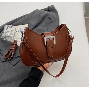 Detail of a brown crescent moon bag showing silver metal buckle and matte PU leather texture