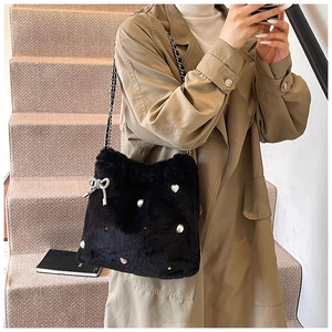 Détail du sac seau en peluche noire avec breloque cœur en perles et nœud scintillant