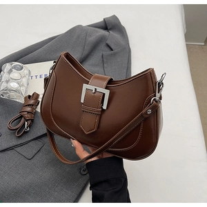 Detail of a deep brown faux leather crescent bag with silver buckle and adjustable strap