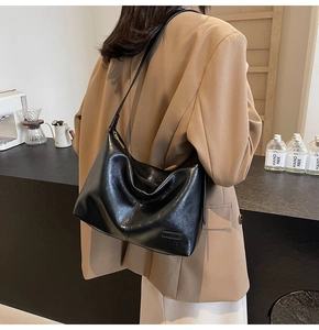Détail du sac hobo noir avec logo métallique sur une texture de cuir lisse raffiné