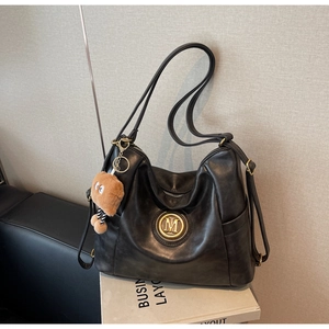 Detail view of black vintage hobo bag with gold M logo and brown bear charm