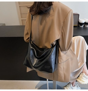 Détail de la texture du sac hobo en cuir noir avec un petit logo métallique sur la surface