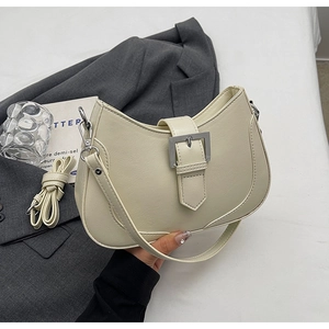 Detail of creamy white crescent shoulder bag with silver buckle and detachable strap