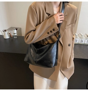 Mannequin portant un grand sac croissant en cuir noir au design plissé souple
