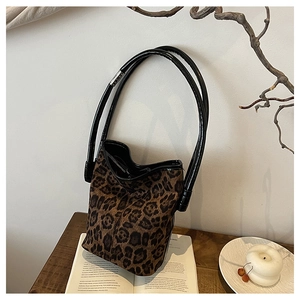 Artistic display of a leopard print bucket bag on an open book with warm lighting decor