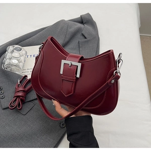 Detail of wine red faux leather handbag with silver square buckle and adjustable strap