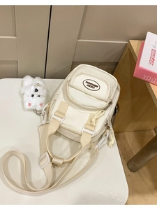 Chic cream canvas crossbody bag with mini plush dog charm and adjustable strap