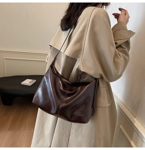Gros plan détaillé du sac bandoulière en cuir marron foncé brillant avec coutures décoratives
