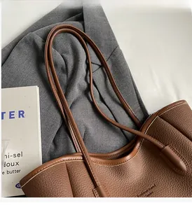Close-up of brown litchi pattern leather tote bag with fine stitching and branding