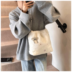 Détail du sac seau en peluche blanche avec nœud en strass et chaîne argentée