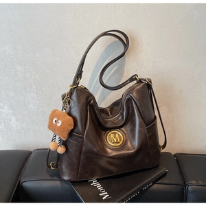 Detail of vintage brown tote bag with golden M-logo and cute plush toast charm