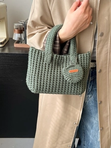 Dark green handmade knit bucket bag with a small coin purse and thick woven texture