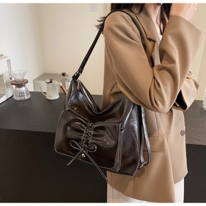 Detail of dark brown shoulder bag with large bow design and visible stitching details