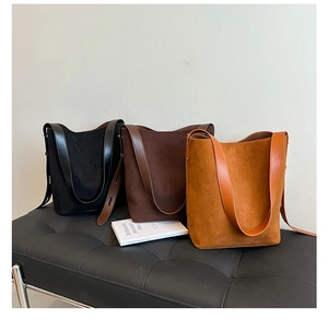Three suede bucket bags in black, coffee, and caramel colors on a leather bench