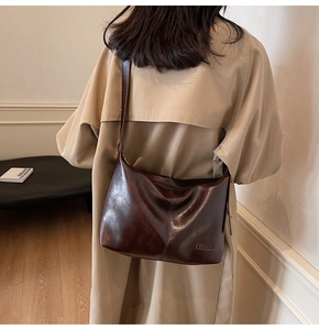 Détails de la texture du cuir marron foncé brillant et surpiqûres sur le sac cabas