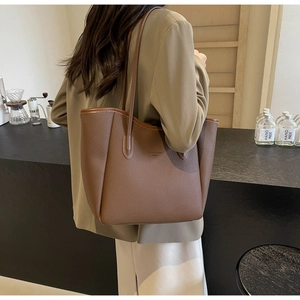 Detail of a brown lychee pattern leather tote bag with elegant brand lettering