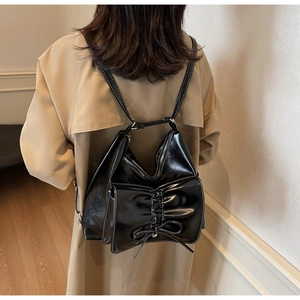 Detail of black glossy leather backpack with contrast stitching and bow design