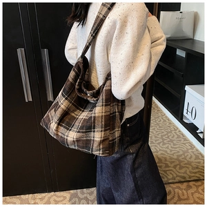 Detailopname van een grote bruine geruite wollen draagtas met casual stedelijke kleding