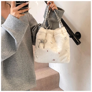 Gros plan du sac seau en peluche blanche avec breloques perles et bandoulière chaîne