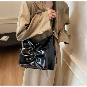 Detail of black glossy tote bag with large bow design and contrast white stitching