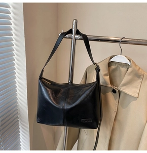 Détail du sac fourre-tout noir en simili cuir avec bandoulière et plaque métallique