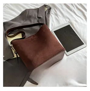 Macro detail of brown suede and smooth leather stitching on a chic bucket shoulder bag