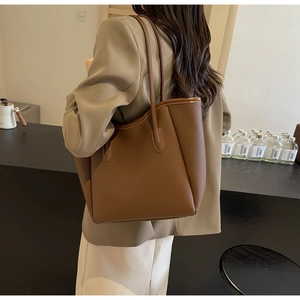 Detail of a brown lychee-textured leather tote bag with long shoulder straps for women