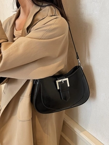 Fashionable black faux leather underarm crescent bag with silver buckle on a model