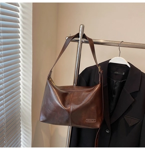 Détail du sac hobo vintage marron foncé avec coutures latérales et logo embossé