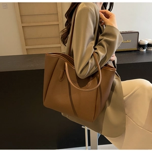 Detail of brown litchi pattern leather tote bag with elegant metallic finish and strap