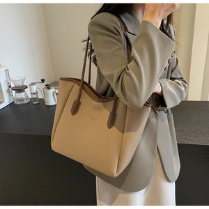 Close-up of minimalist beige tote bag with lychee texture and brown handle detail