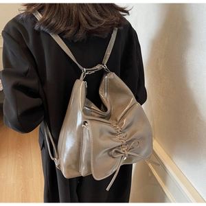 Detail of glossy leather backpack with soft bow design on black coat model