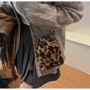 Detail of plush leopard print bucket bag with drawstring strap on a fashion model