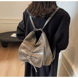 Detailed back view of a taupe leather backpack featuring a large bow and soft pleats