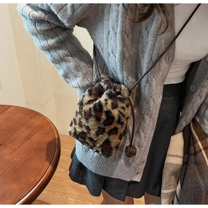 Detail view of leopard print plush bucket bag with drawstring closure and leather strap